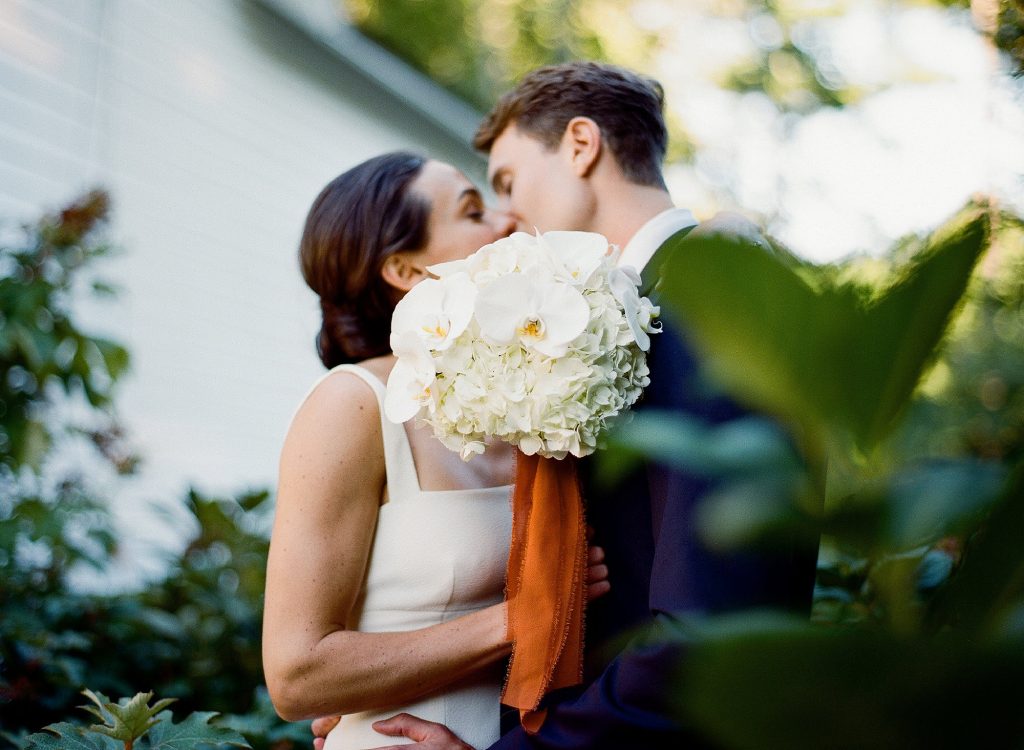 wedding couple kiss behind shrubbery CT